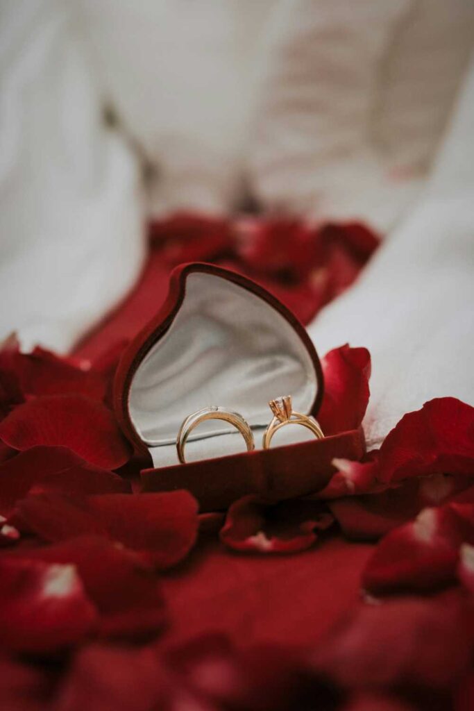 Close-up photo of two wedding rings nestled inside a heart-shaped box (Wedding Details Photography)